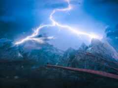 молния ударяет по горной вершине с одинокой птицей, сидящей на уступе