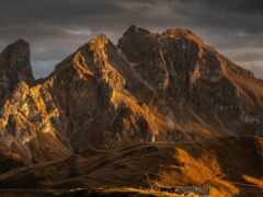 горы с несколькими коровами, пасущимися в траве возле озера