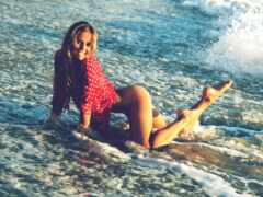 есть женщина, которая лежит на доске для серфинга в воде