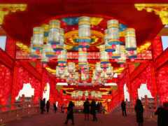 люди идут под красочной аркой с висящими на ней фонарями