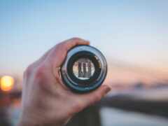 кто-то держит объектив камеры, чтобы сфотографировать закат