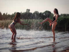 две женщины в купальниках играют в воде друг с другом