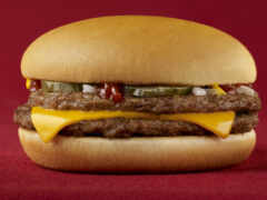 гамбургер с сыром и соленьями на красной поверхности