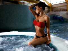 женщина в красном бикини сидит в горячей ванне