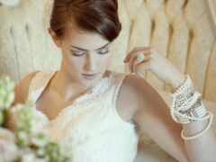 невеста в белом платье сидит на стуле с букетом цветов