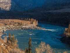 есть поезд, который едет по рельсам возле реки