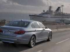 женщина-автомобиль едет по шоссе с круизным судном на заднем плане