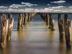 женщина деревянные столбы в воде с облаками в небе