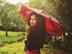 женщина держит в парке зонтик