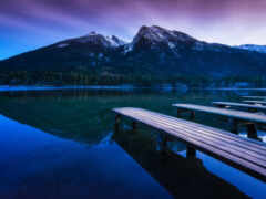 горы отражаются в воде озера со скамейками