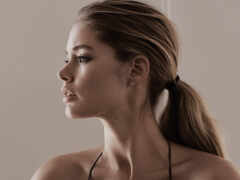 блондинка с хвостиком в черном бикини смотрит в сторону от камеры