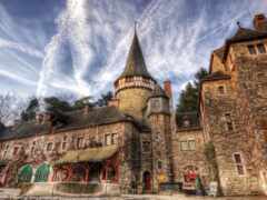 вид на замок с башней с часами и фонтаном