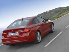 женский вид красного автомобиля bmw, едущего по горной дороге