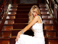 блондинка в белом платье сидит на лестнице в здании
