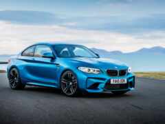 голубое купе bmw m140i, движущееся по дороге у океана