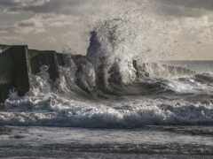 арафы волн, разбивающихся о бетонную стену на пляже