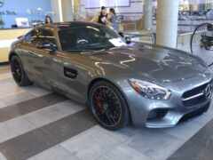 женщина мерседес спортивный автомобиль припаркован в выставочном зале с людьми, проходящими мимо