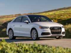 белый автомобиль audi, едущий по дороге возле холма