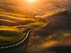 вид с воздуха на извилистую дорогу в холмистой местности с закатом