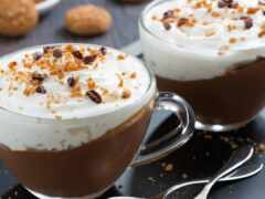 есть две чашки кофе со взбитыми сливками и шоколадными чипсами