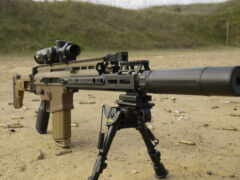 винтовка с прицелом и штативом на пустынной земле