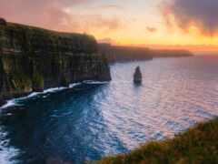 женщина скалы на краю скалы с закатом на заднем плане