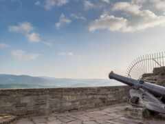 на каменной стене есть пушка с видом на гору