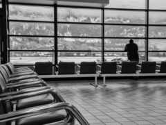 в зале ожидания стоит мужчина с видом на горы