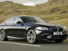 женщина чернокожего седана bmw m5 едет по дороге в горы