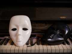 есть две маски, сидящие на клавиатуре фортепиано рядом с пианино