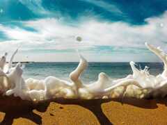 арафляйная пенистая волна разбивается о пляж с голубым небом