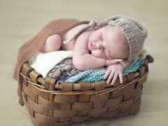 ребенок спит в корзине с шляпой