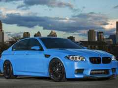 женщина голубого цвета bmw m5 припаркована перед горизонтом города