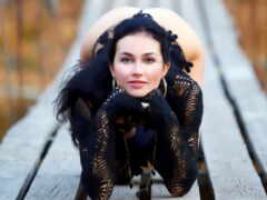 женщина сидит на деревянном мосту с руками на коленях