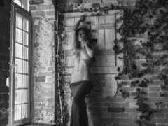 женщина без рубашки, прислоненная к кирпичной стене в комнате