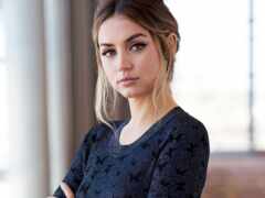 блондинка с серьезным взглядом на лице стоит в комнате