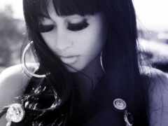 женщина с длинными черными волосами и серьгами смотрит вниз