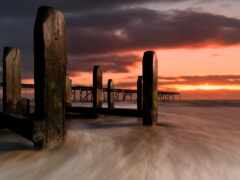 женщина деревянные столбы в воде на закате возле пирса