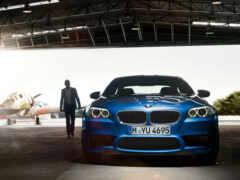 женщина-мужчина, стоящая рядом с синей машиной bmw в ангаре