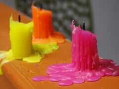 ярко окрашенные свечи сидят на столе с цветком