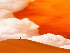 есть человек, идущий по песчаной дюне в пустыне