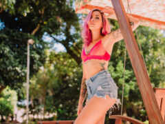 женщина с розовыми волосами и татуировками на качелях