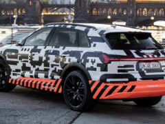 женщина-сув припарковалась перед большим зданием с мостом на заднем плане