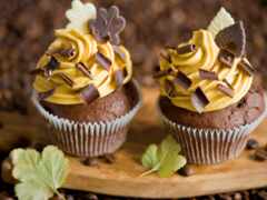 есть два кекса с шоколадом и желтой глазурью на деревянной доске