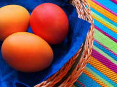 три яйца в корзине на красочной скатерти
