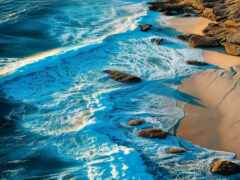 женский вид на пляж с камнями и водой