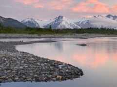 горы отражаются в воде реки на закате