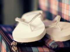 на чемодане сидит пара белых сандалий