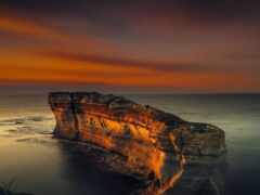 женщина скалообразование в океане на закате с небесным фоном