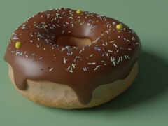 есть шоколадный мороженый пончик с посыпками на зеленой поверхности